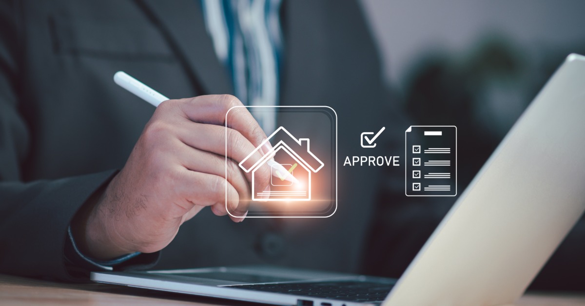 A close-up of a business man sitting at a computer with a tablet pen in hand and an abstract home image with the word "approve."