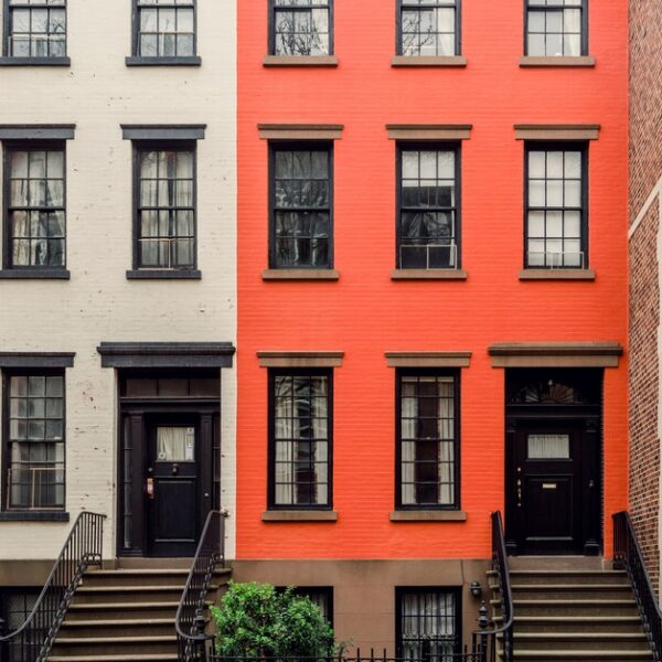 The facades of several neighborhood homes next to each other in different colors on a New York Street.